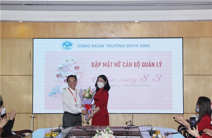 Đ/c Nguyễn Thị Quỳnh Nga -Chủ tịch Công đoàn trường - đón nhận bó hoa tươi thắm từ PGS.TS. Nguyễn Cảnh Phú - Bí thư, Đảng ủy nhà trường - trao tặng